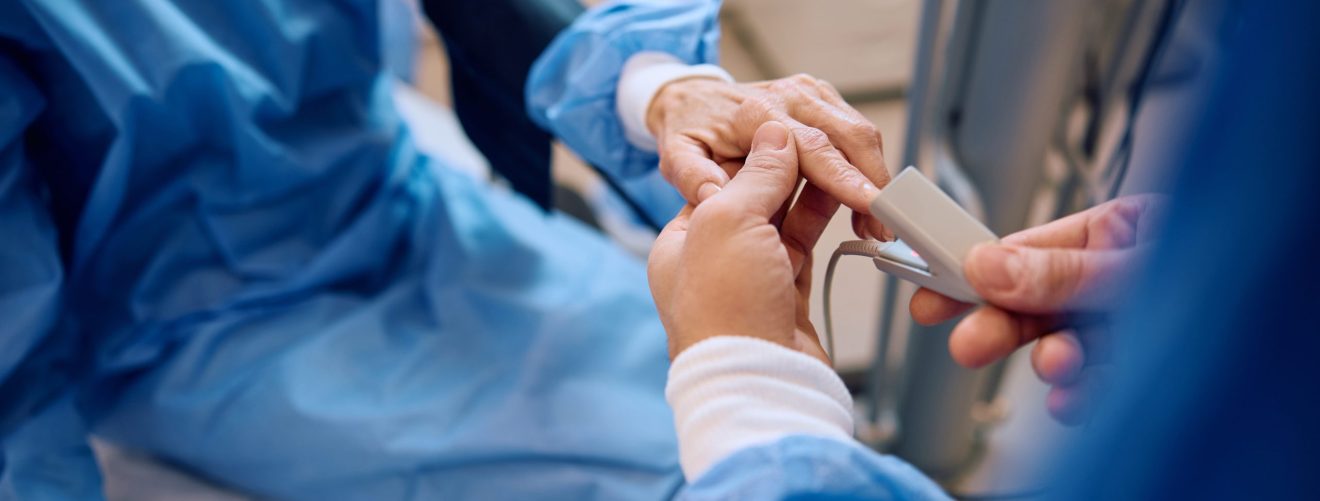 Close up of medical technician putting pulse oximeter on patient's finger before surgery at clinic.